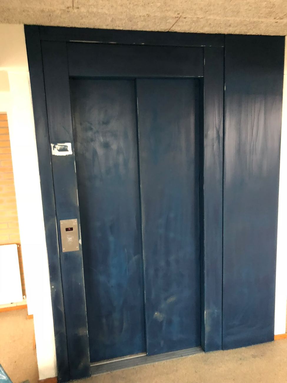 Versleten liftdeuren in een appartementencomplex vóór renovatie