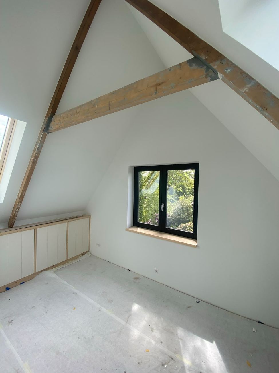 Wit gespoten plafond en kapconstructie met houten balken