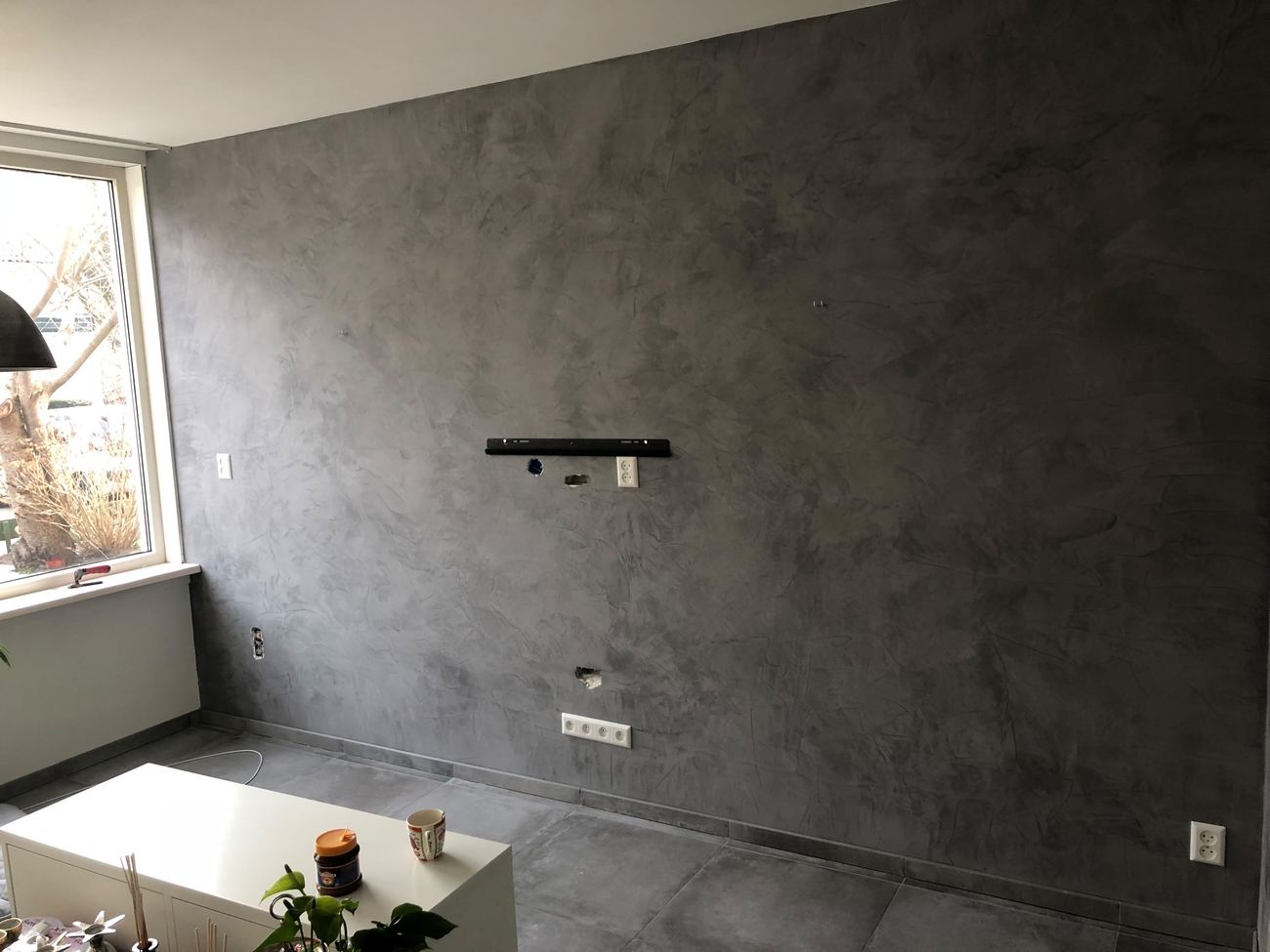 Donkergrijze stucco wand als tv-wand in de woonkamer